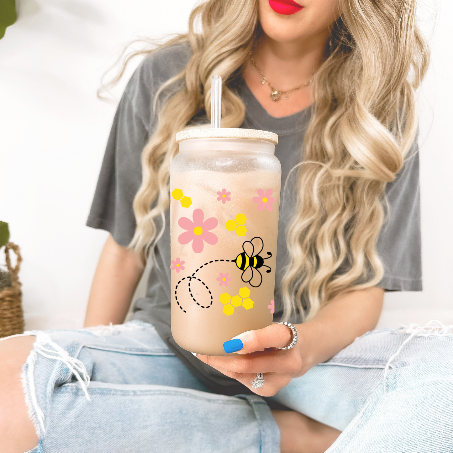 Person holding a tumbler with floral design and bee illustration