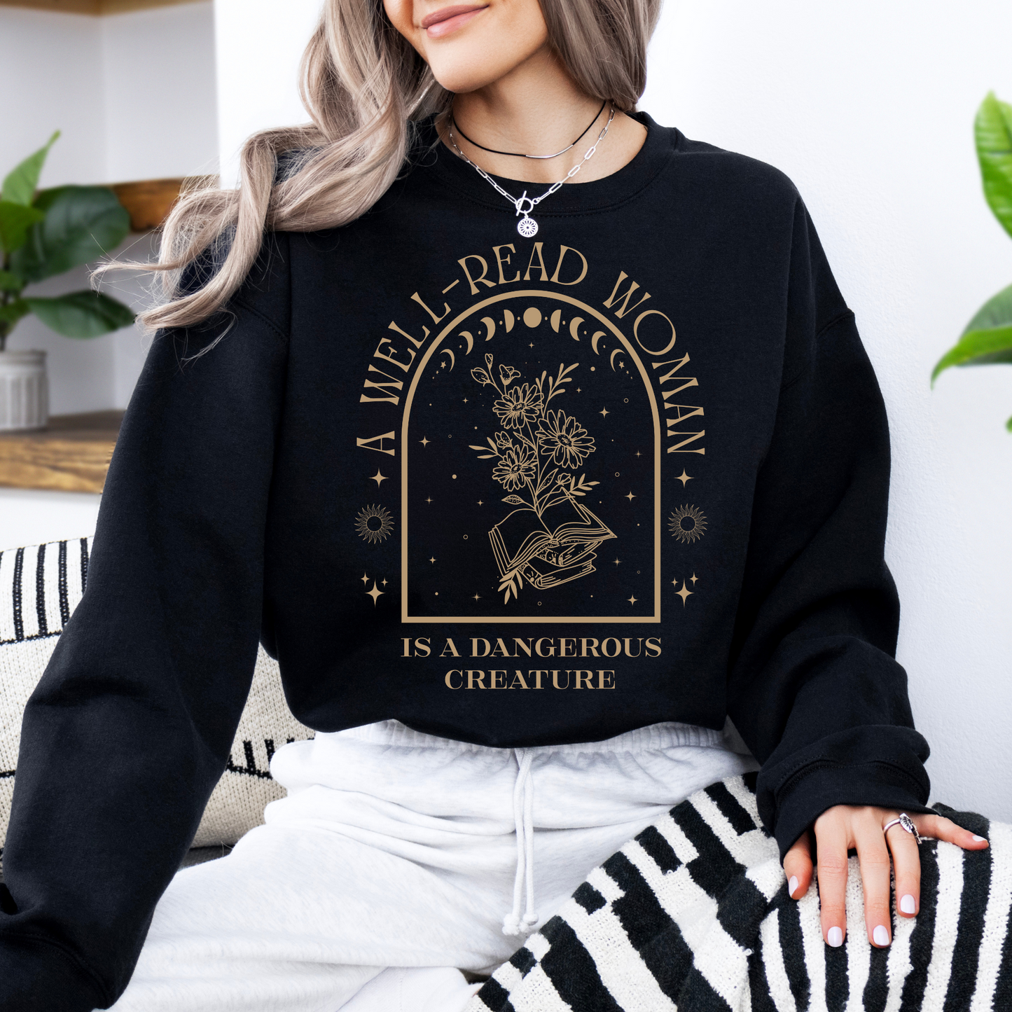 Person wearing a black sweatshirt with 'A Well-Read Woman is a Dangerous Creature' text and design.
