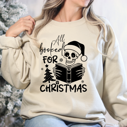Beige sweatshirt with a skull design and text 'All booked for Christmas' held by a person.