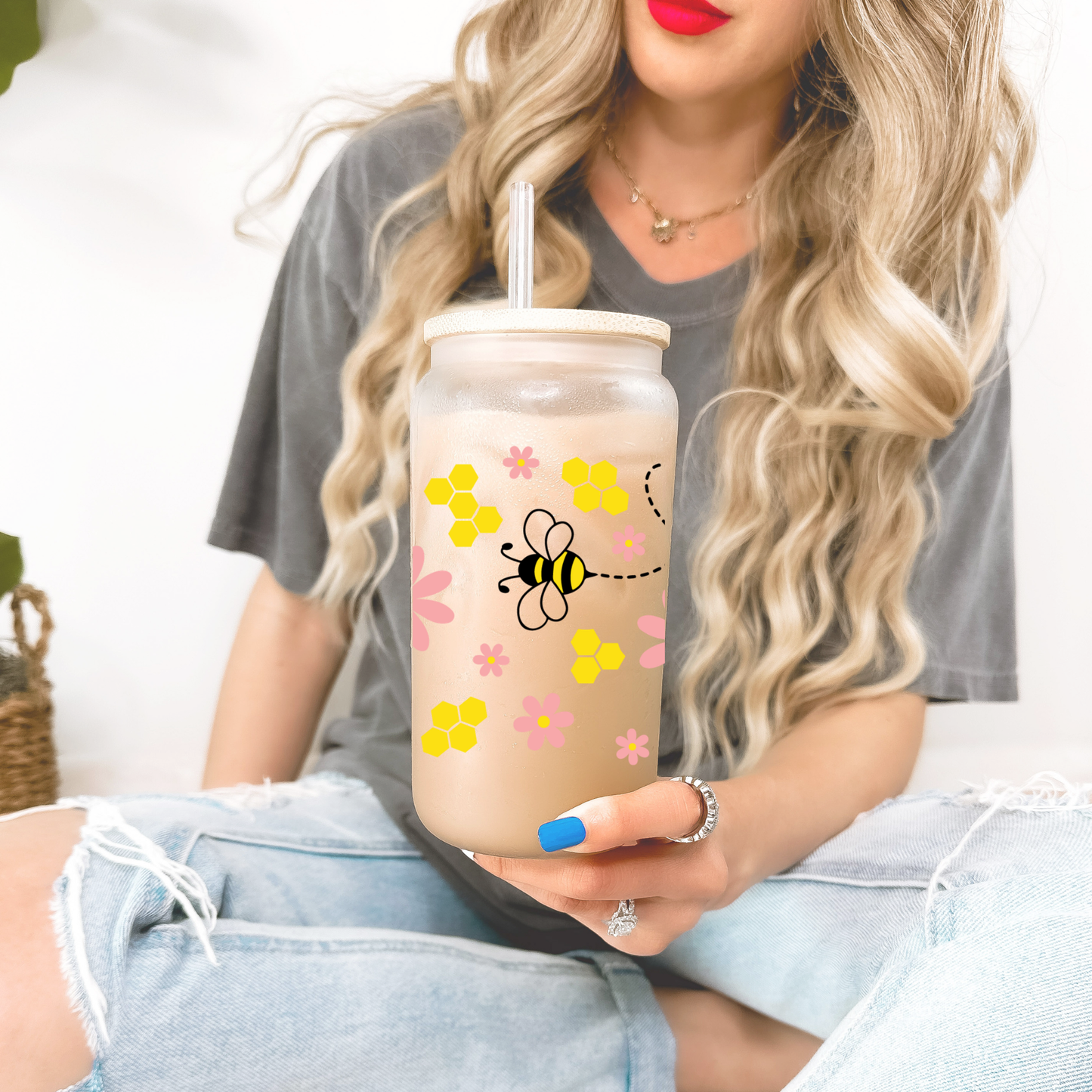 Person holding a tumbler with a bee and flower design.