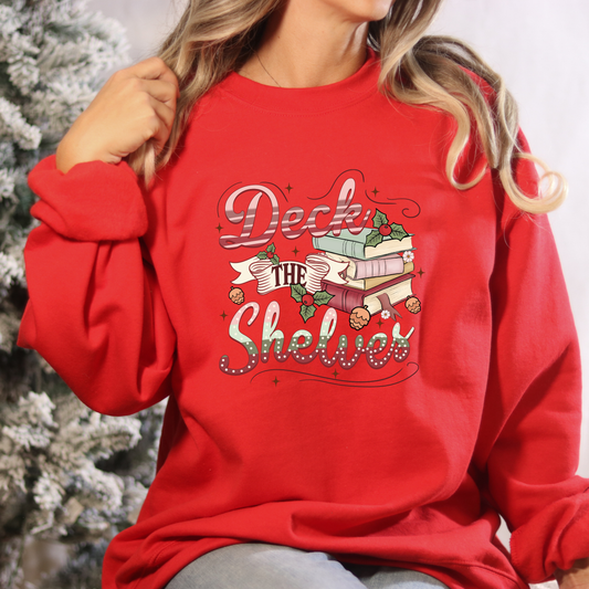 Red sweatshirt with 'Deck the Shelves' text and Christmas-themed design, worn by a person.