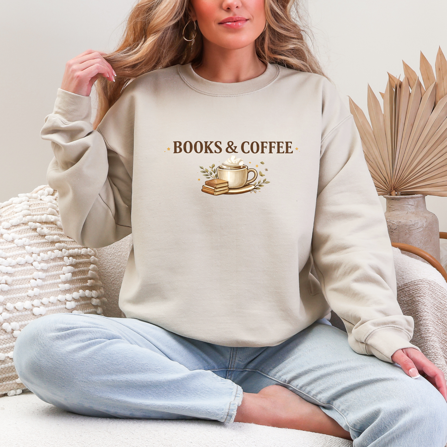Person wearing a beige sweatshirt with 'BOOKS & COFFEE' text and graphics, sitting on a couch.