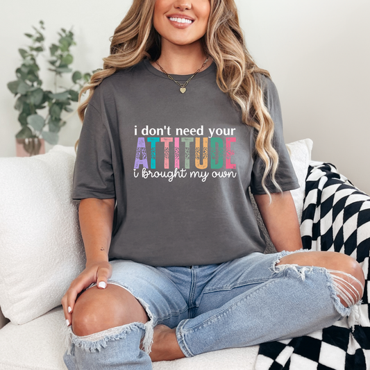 Person wearing a gray t-shirt with colorful text sitting on a couch.