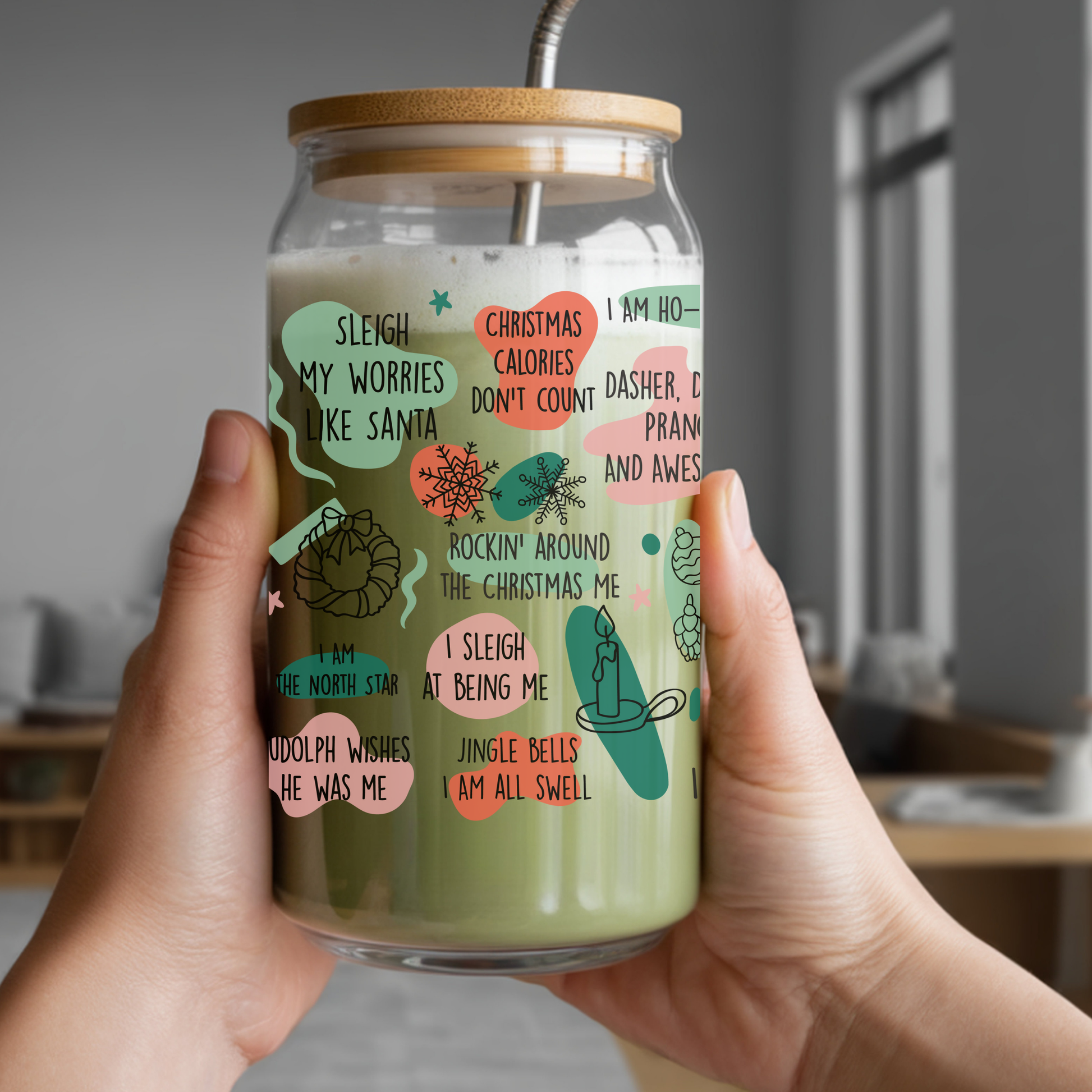 Glass jar with a straw lid, filled with a green beverage, held by hands indoors.