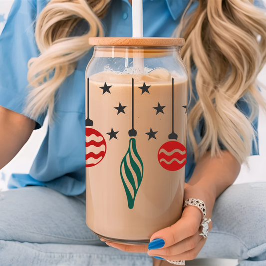 Person holding a glass cup with a festive design, sitting on a light blue couch.