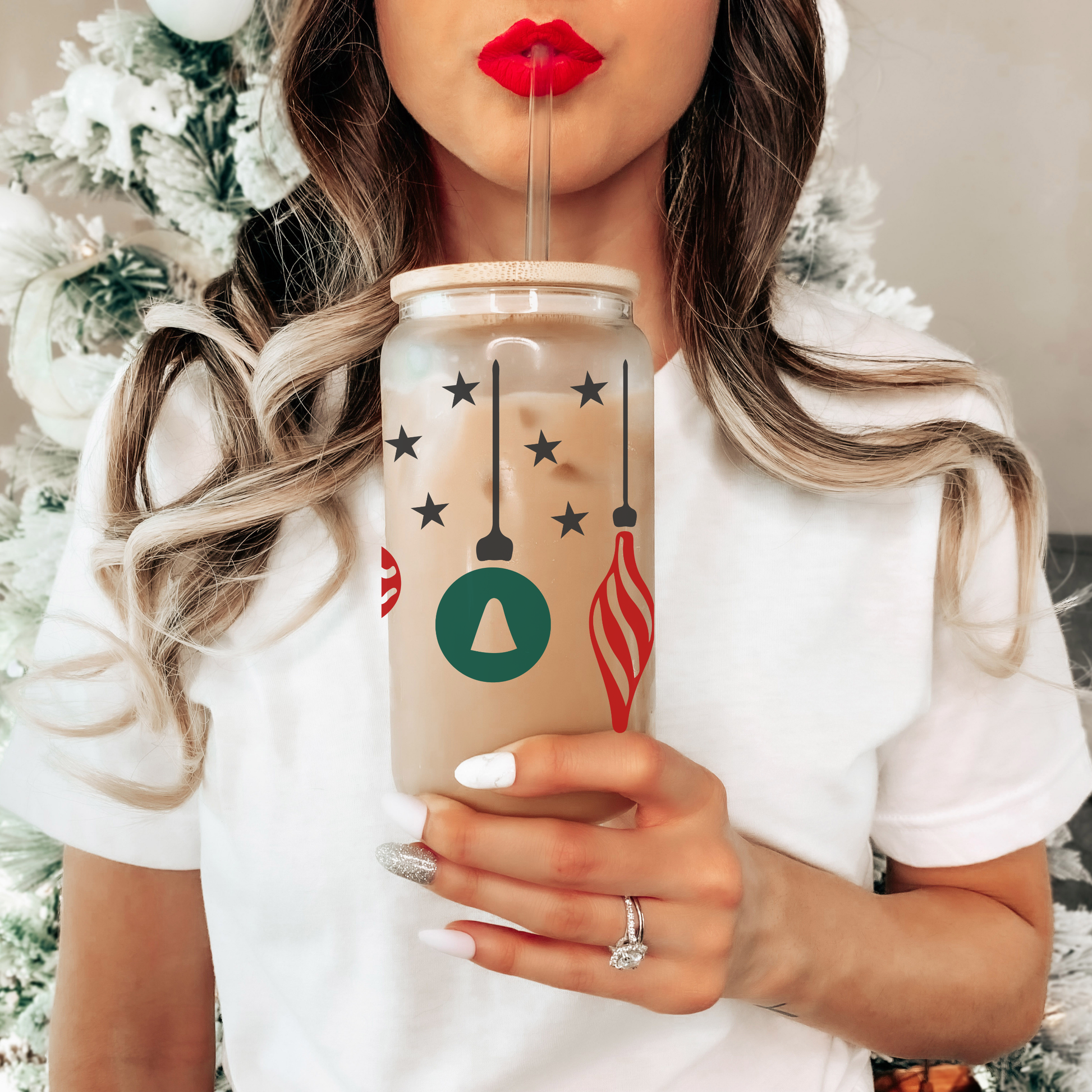 Person holding a festive-themed tumbler with Christmas decorations, wearing a white sweater.