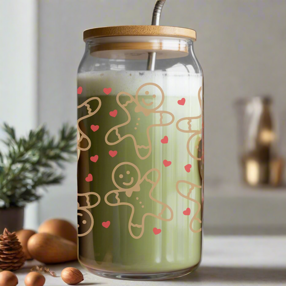 Person holding a glass jar with a gingerbread man design filled with a green beverage.