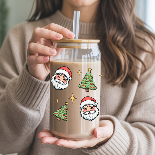 Person holding a glass mug with Christmas-themed illustrations and a straw.