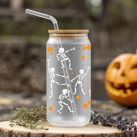 Clear glass tumbler with skeleton design and straw on a wooden surface with a blurred background