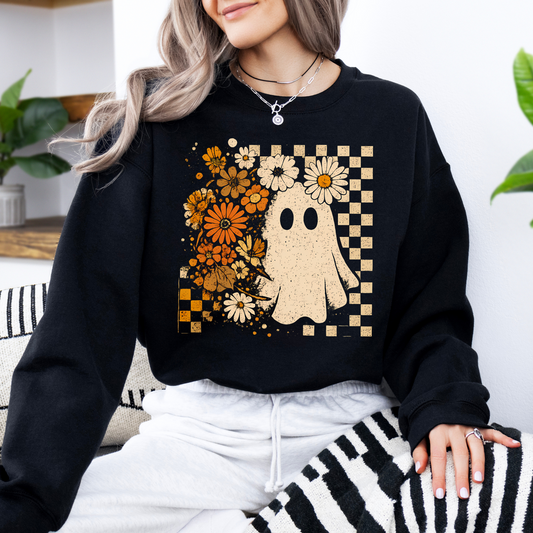 Person wearing a black sweatshirt with a ghost and floral design, sitting on a striped surface.