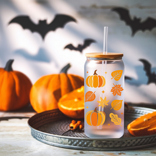 Transparent tumbler with pumpkin and leaf patterns on a Halloween-themed background with pumpkins and bats.