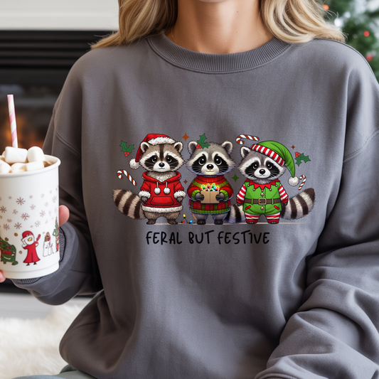 Person wearing a sweater with Christmas-themed raccoons and holding a hot chocolate cup.