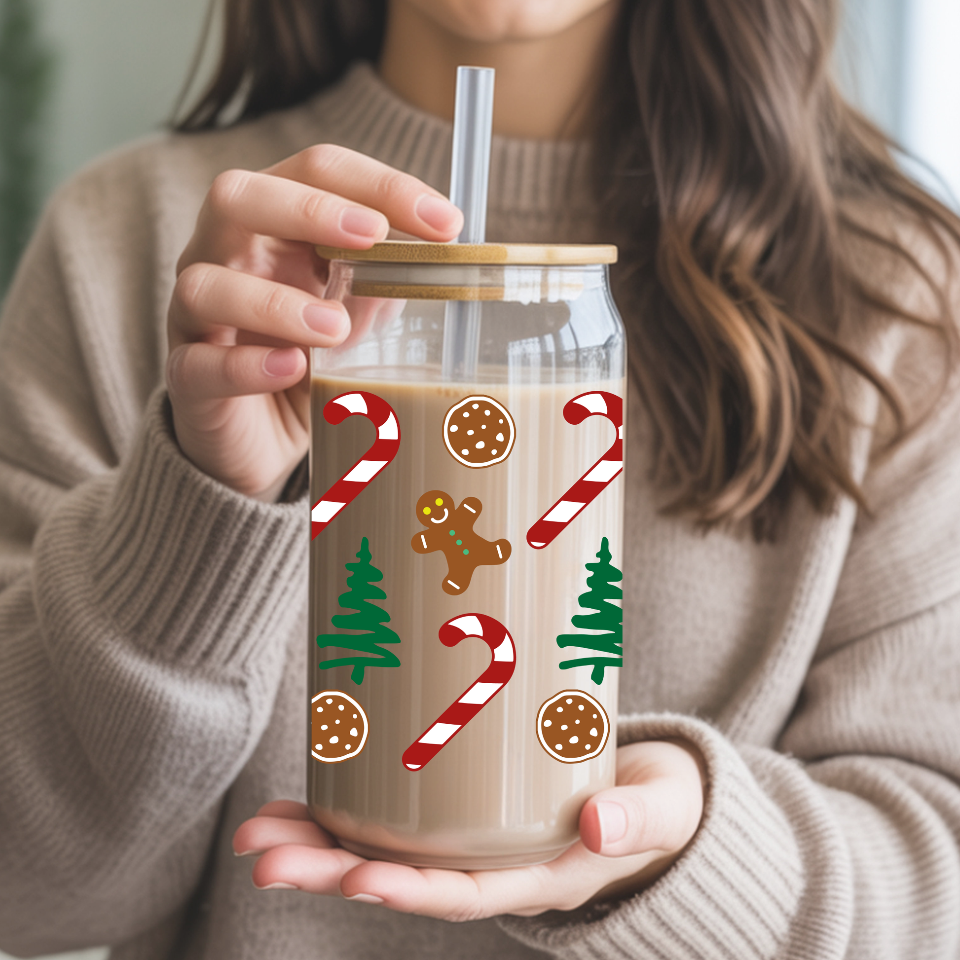 Person holding a glass tumbler with Christmas-themed designs