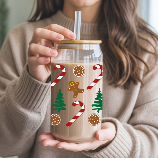 Person holding a glass tumbler with Christmas-themed designs