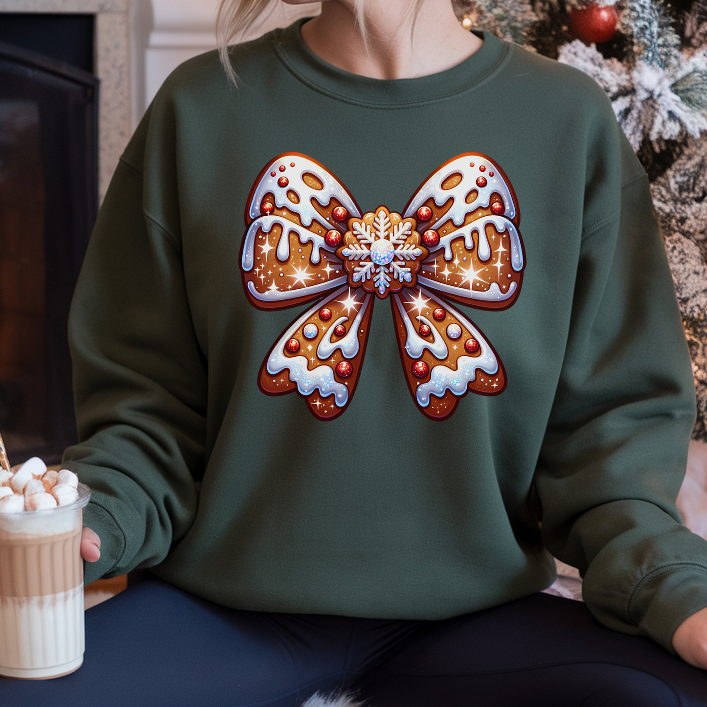 Person wearing a green sweatshirt with a large decorative bow design, sitting in front of a Christmas tree.