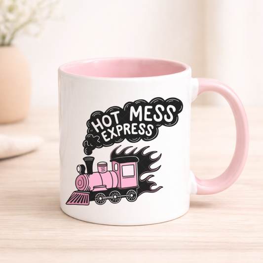 White mug with pink interior and handle, featuring a train design and 'Hot Mess Express' text.
