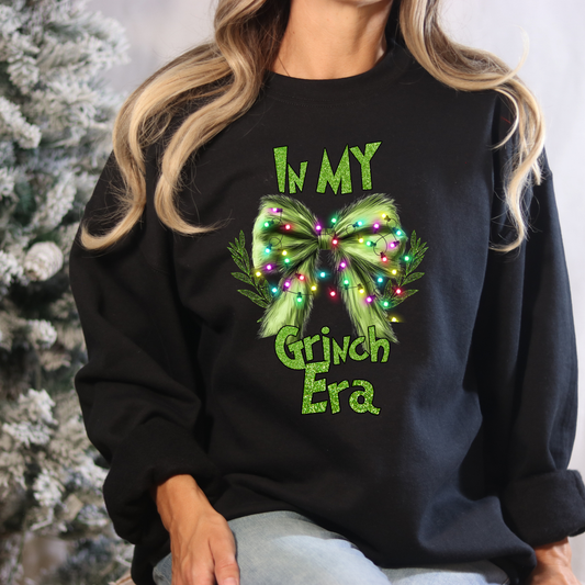 Person wearing a black sweatshirt with a festive design and text, sitting in front of a Christmas tree.