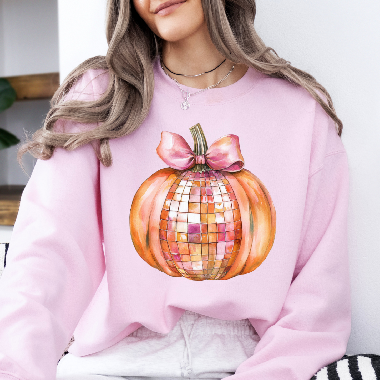 Person wearing a pink sweatshirt with a disco pumpkin design.