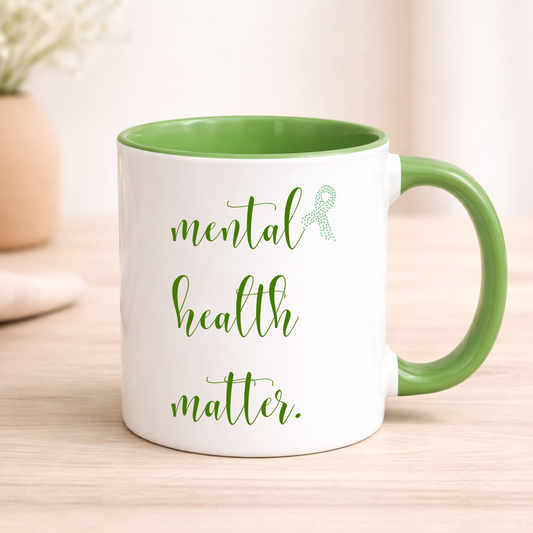 Mug with 'mental health matters' text and green ribbon on a wooden surface