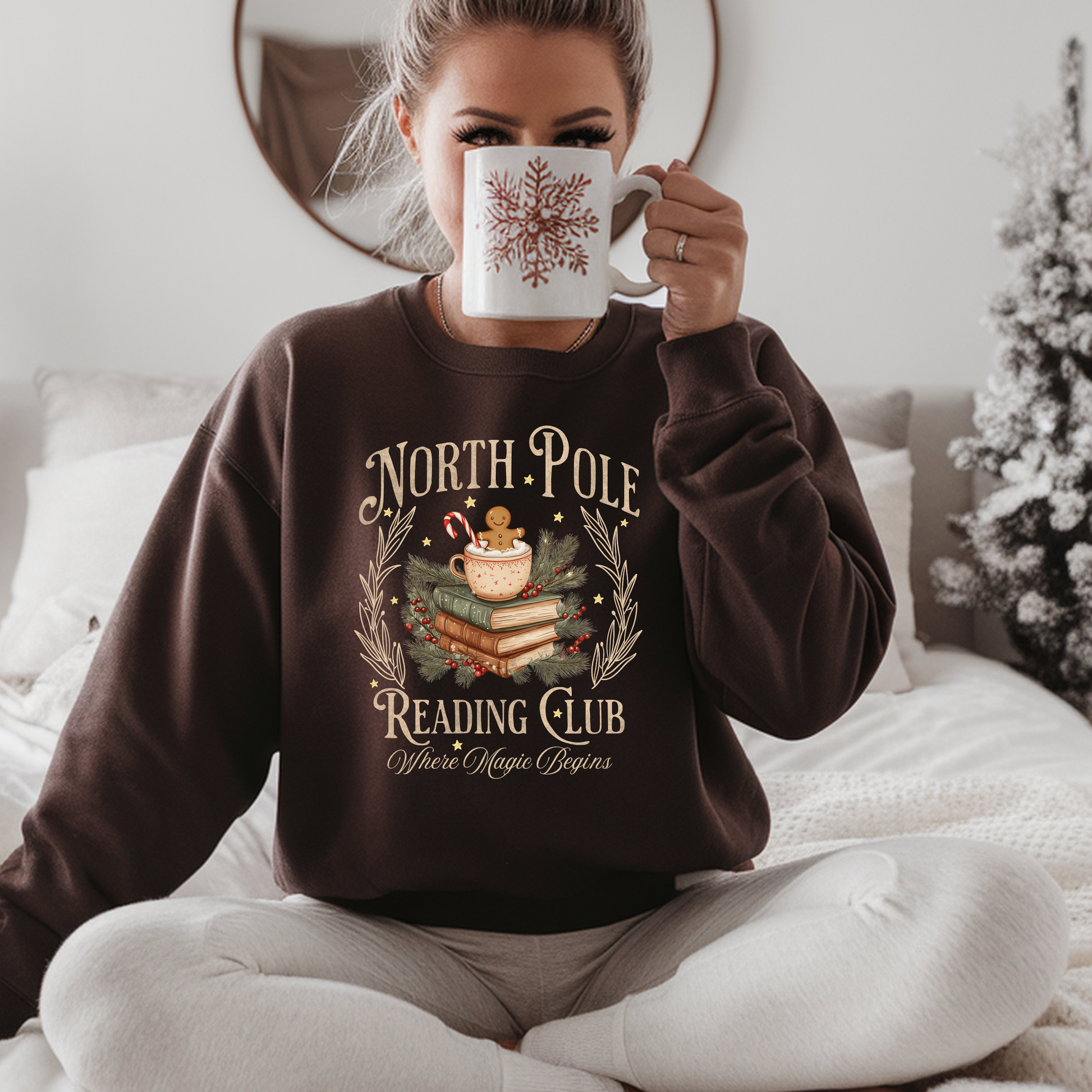 Person wearing a 'North Pole Reading Club' sweatshirt holding a mug.