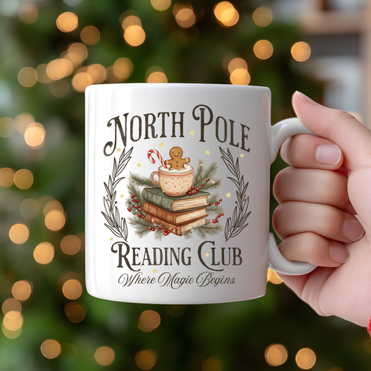 Mug with 'North Pole Reading Club' design held in front of a Christmas tree.
