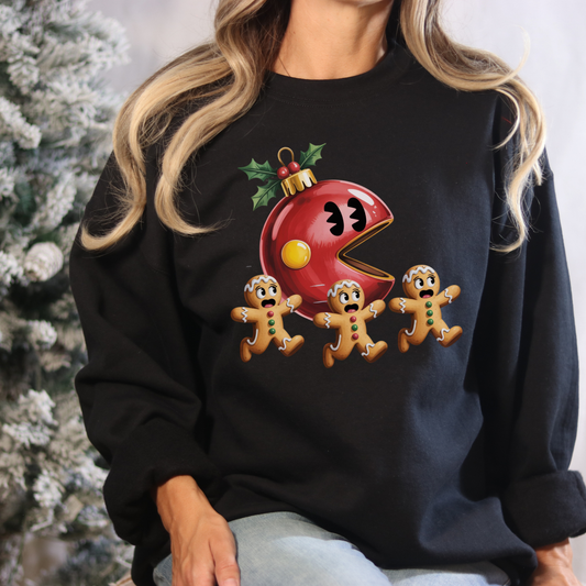 Person wearing a black sweatshirt with a Christmas-themed design featuring a red ornament and gingerbread men.