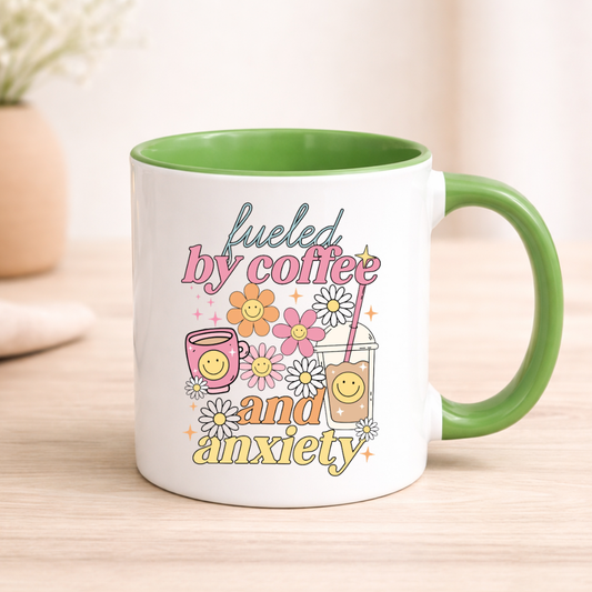 Mug with 'fueled by coffee and anxiety' text and floral graphics on a wooden surface.
