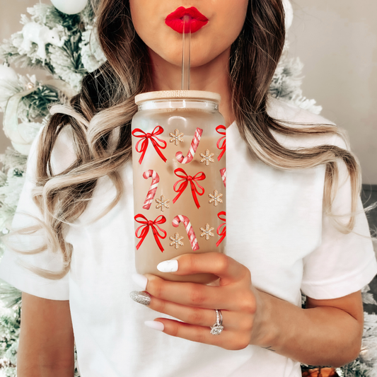 Person holding a festive drink with red bows and candy canes, wearing a white sweater.